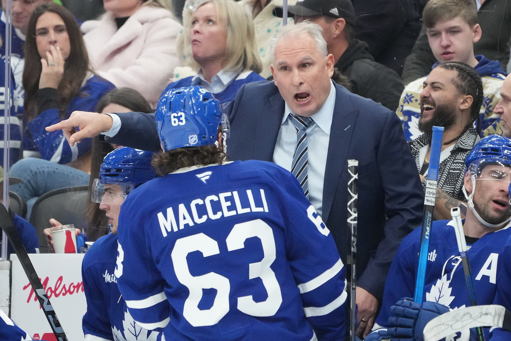 Toronto Maple Leafs head coach Craig Berube talks to forward Matias MacCelli (63) during second period NHL hockey action against the Pittsburgh Penguins in Toronto on Tuesday, Dec. 23, 2025. (Nathan Denette/The Canadian Press via AP)