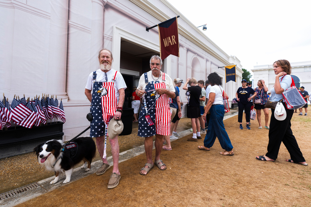 Visitors at the Great American State Fair Jason Gentry, from left, and Jim Vlahos, of Galveston, Texas, walk with their service dog, after a visiting the Department of Defense booth, on the National Mall, Wednesday, July 8, 2026, in Washington. (AP Photo/Manuel Balce Ceneta)