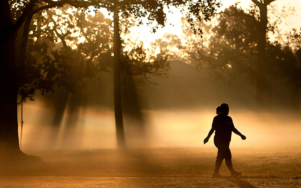 FILE - A woman walks down a trail as fog looms at Montie Beach Park in Houston, on Monday, Oct. 17, 2011. (Cody Duty/Houston Chronicle via AP, File)
