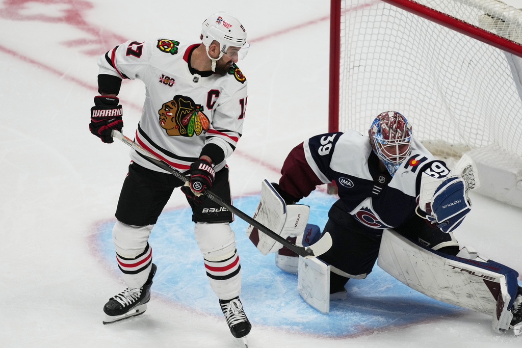 Chicago Blackhawks left wing Nick Foligno, left, redircts a shot into the glove of Colorado Avalanche goaltender MacKenzie Blackwood in the third period of an NHL hockey game Saturday, Feb. 28, 2026, in Denver. (AP Photo/David Zalubowski)