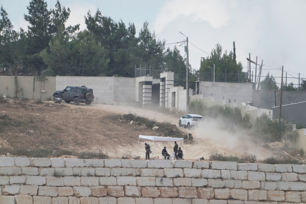 Israeli soldiers sit under a tent in front of the house of Ohio-based Palestinian-American landlord Loui Ridi, that is besieged by Israeli settlers for over a week, in the occupied West Bank village of Qusra, south of Nablus, Tuesday, Aug. 18, 2026. (AP Photo/Majdi Mohammed)