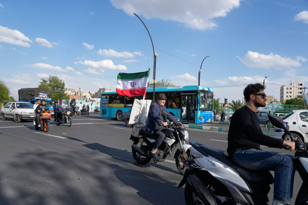 A man rides his motorbike that is adorned with an Iranian national flag, in southern Tehran, Iran, Tuesday, April 21, 2026. (AP Photo/Vahid Salemi)