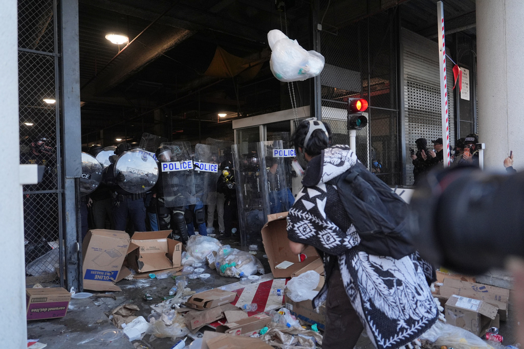 Protesters throw trash at federal police blocking a loading dock at the Metropolitan Detention Center in downtown Los Angeles on Friday, Jan. 30,2026. (AP Photo/Jae C. Hong)