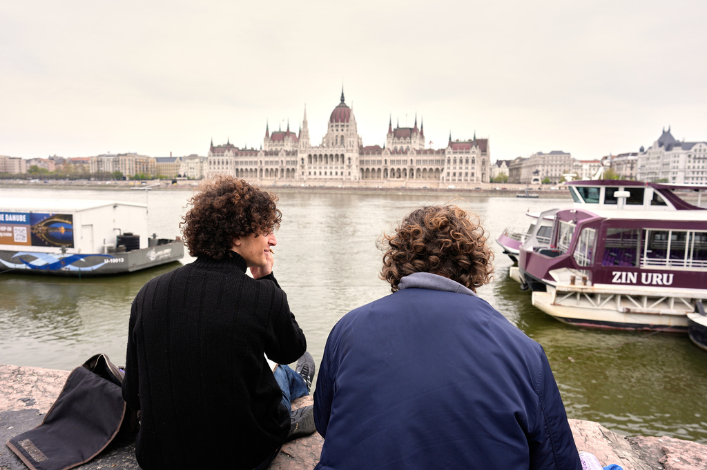Hungarian students Kristof, left, 19 years-old, and Vincent, 20 years-old, paint by the Danube river, backdropped by the parliament building in Budapest, Hungary, Monday, April 13, 2026, after Peter Magyar's Tisza party defeated Prime Minister Viktor Orban's Fidesz party in the country's parliamentary elections. (AP Photo/Petr David Josek)