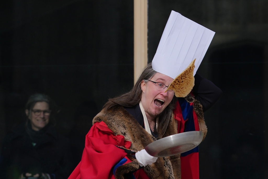 A competitor participates in a traditional pancake race by livery companies at the Guildhall in London, Tuesday, Feb. 17, 2026. (AP Photo/Kin Cheung)