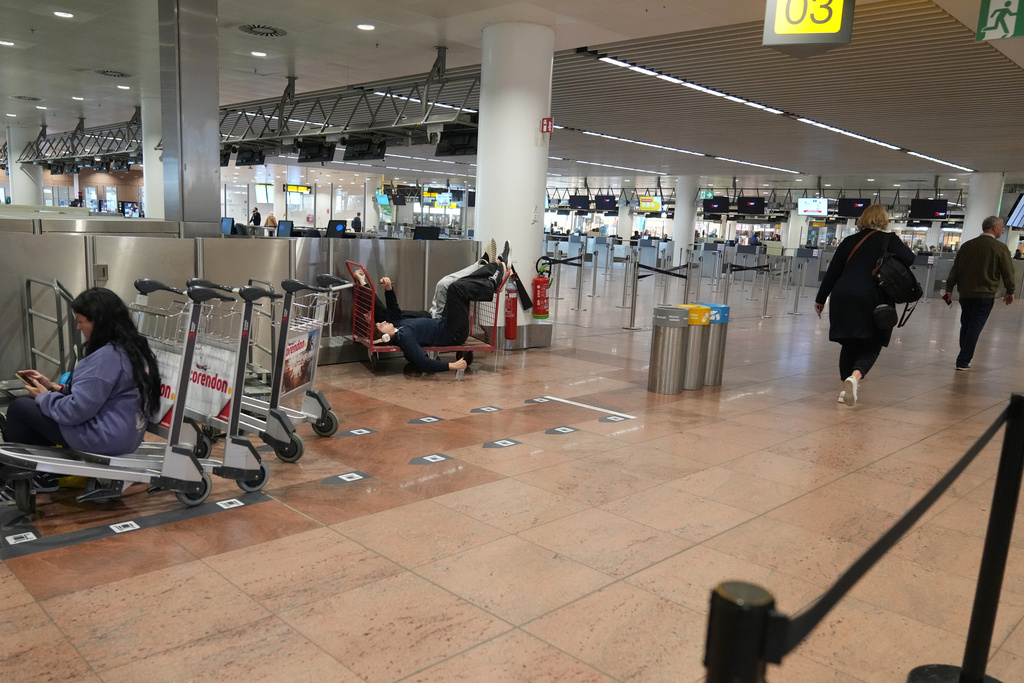 Passengers pass the time after several cancellations and delays due to reported overnight drone activity over Brussels International Airport in Zaventem, Wednesday, Nov. 5, 2025. (AP Photo/Virginia Mayo)