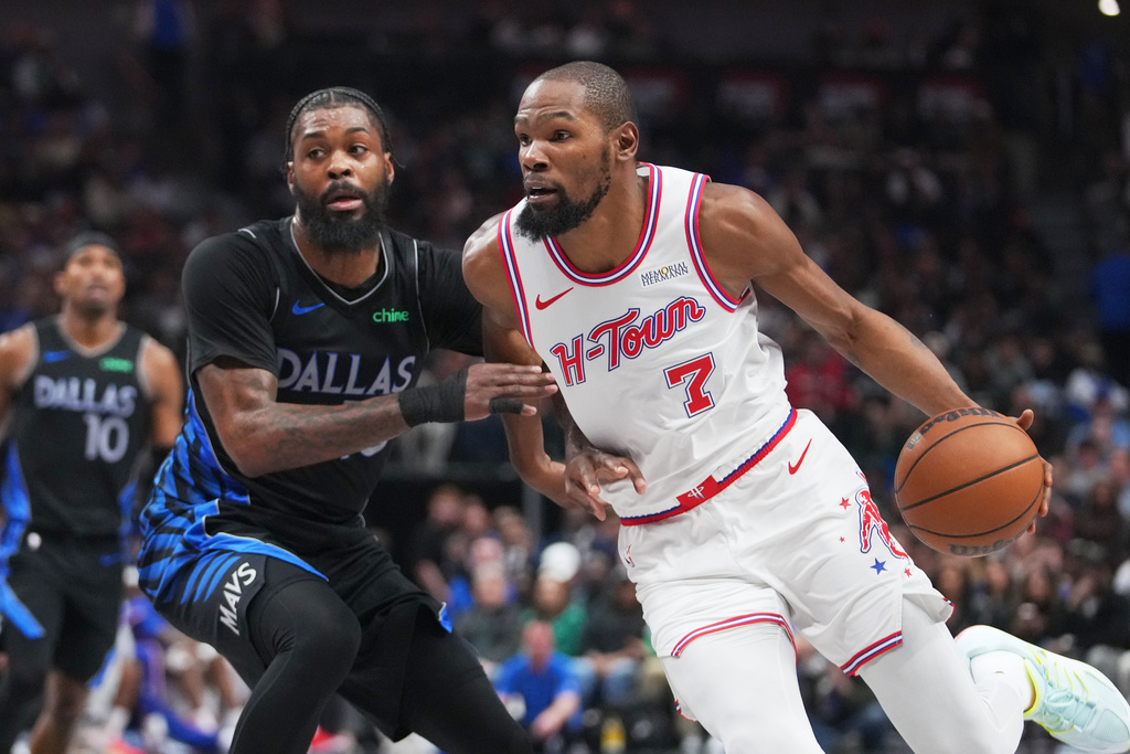 Houston Rockets forward Kevin Durant, right, drives to the basket against Dallas Mavericks forward Naji Marshall during the first half of an NBA basketball game Saturday, Jan. 3, 2026, in Dallas. (AP Photo/Julio Cortez)