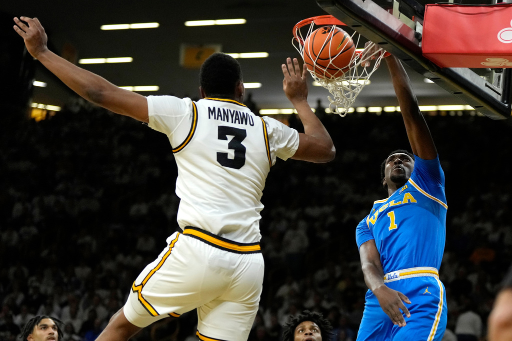 UCLA center Xavier Booker (1) dunks the ball in front of Iowa forward Cam Manyawu (3) during the first half of an NCAA college basketball game, Saturday, Jan. 3, 2026, in Iowa City, Iowa. (AP Photo/Charlie Neibergall)