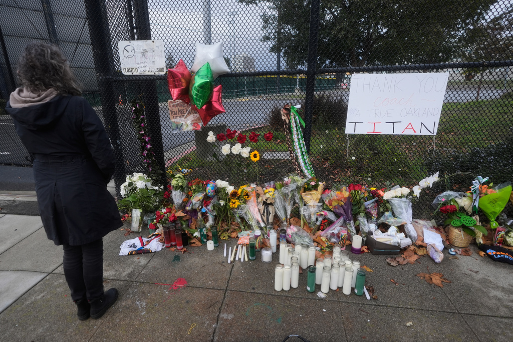 Jayne Moser looks at a sidewalk memorial for former football coach John Beam at Laney College, in Oakland, Calif., Monday, Nov. 17, 2025. (AP Photo/Jeff Chiu)