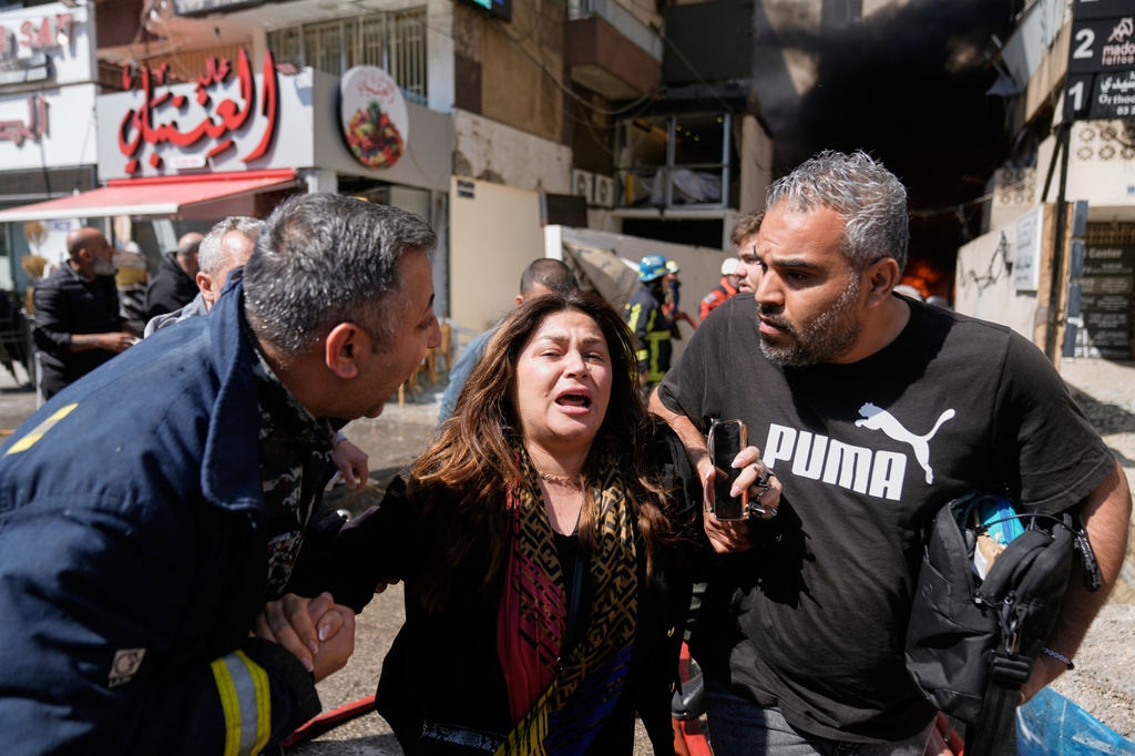 A woman is assisted at the site of an Israeli airstrike that struck an apartment building in Beirut, Lebanon, Wednesday, April 8, 2026. (AP Photo/Bilal Hussein)