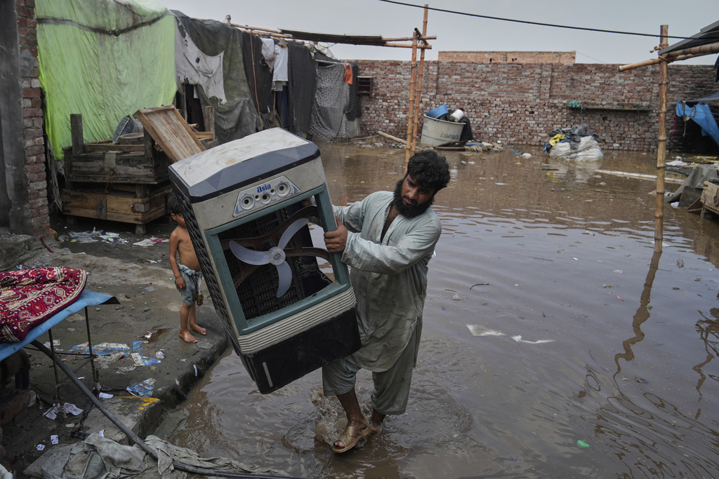 A resident retrieves a room cooler and other belongings from his flooded home due to rising water level in Ravi River after torrential rains at a low-lying area on the outskirts of Lahore, Pakistan, Aug. 28, 2025. (AP Photo/K.M. Chaudary)