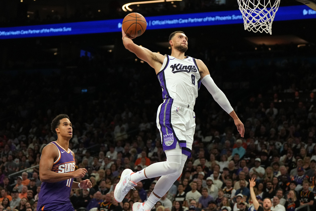 Sacramento Kings guard Zach LaVine (8) dunks over Phoenix Suns forward Oso Ighodaro during the first half of an NBA basketball game, Wednesday, Oct. 22, 2025, in Phoenix. (AP Photo/Rick Scuteri)