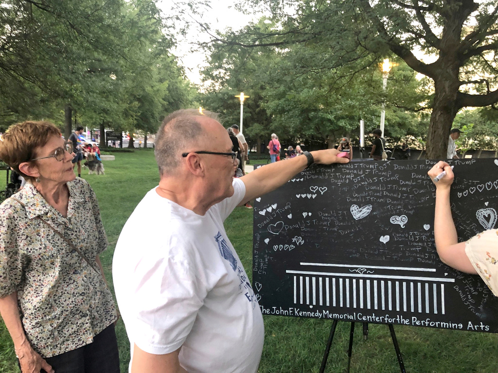 Bud Wilkinson, a member of the local art community, offers protesters at the John F. Kennedy Center for the Performing Arts a chance to erase the President's name and replace it with hearts, Friday, Sept. 18, 2026, in Washington. (AP Photo/Gary Fields)