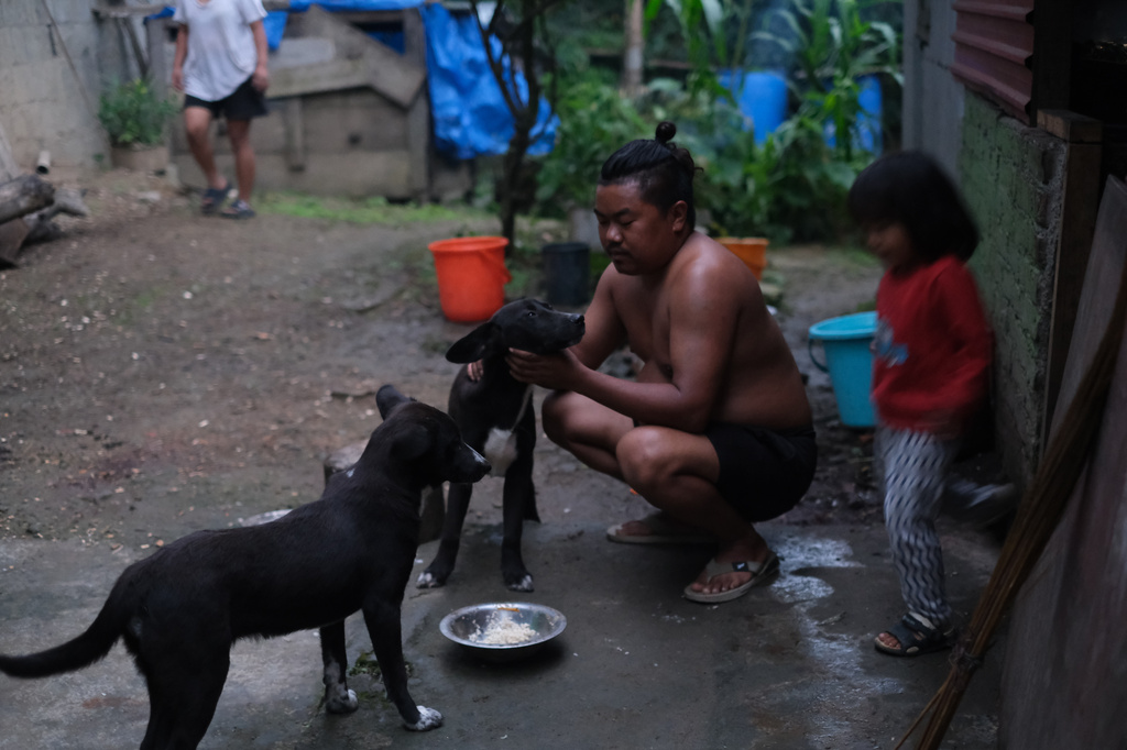 Tovi Murru, 32, pets his dog with his daughter Azatina, 3, by his side in Kohima, capital of the northeastern Indian state of Nagaland, Monday, July 6, 2026. (AP Photo/Yirmiyan Arthur)
