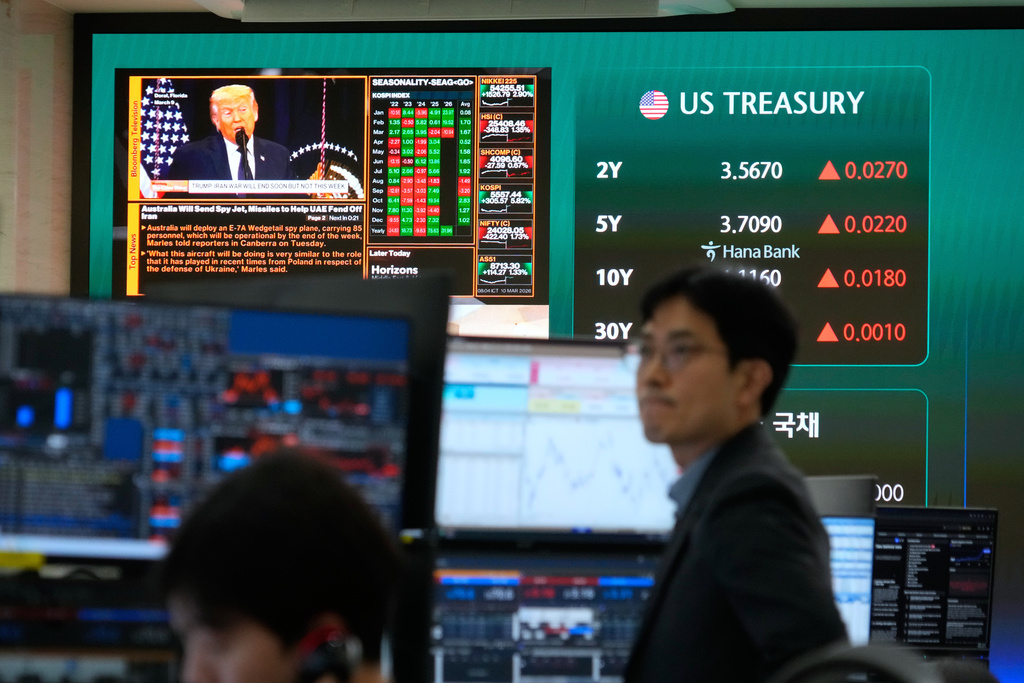 U.S. President Donald Trump is seen on a screen as traders work at the foreign exchange dealing room of the Hana Bank headquarters in Seoul, South Korea, Tuesday, March 10, 2026. (AP Photo/Ahn Young-joon)