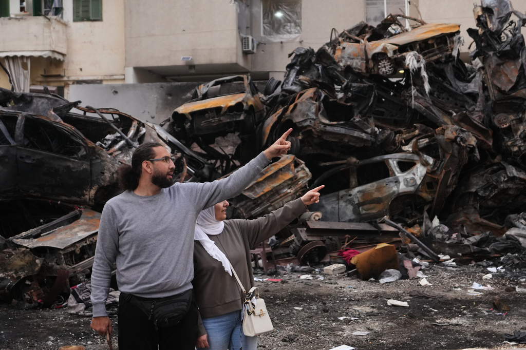 Residents gesture and point toward damage as they stand near charred cars at the site of a building destroyed in an Israeli airstrike last Wednesday in central Beirut, Lebanon, Tuesday, April 14, 2026. (AP Photo/Hassan Ammar)