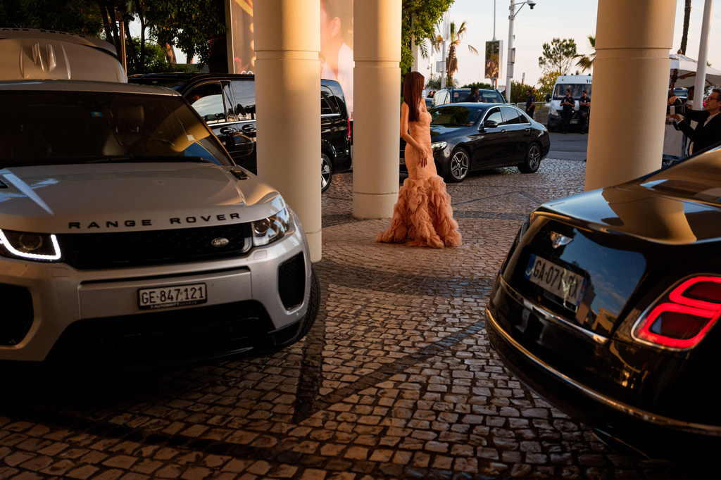 A woman poses for a photographer in the parking lot of Hotel Martinez as cars line up to take festivalgoers to the 79th international film festival, Cannes, southern France, Tuesday, May 19, 2026. (AP Photo/Andreea Alexandru)