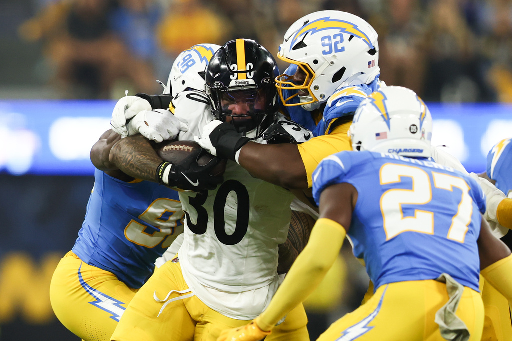 Pittsburgh Steelers running back Jaylen Warren (30) is grabbed by Los Angeles Chargers defensive tackle Justin Eboigbe (92) and linebacker Odafe Oweh (98) during the first half of an NFL football game Sunday, Nov. 9, 2025, in Inglewood, Calif. (AP Photo/Jessie Alcheh)
