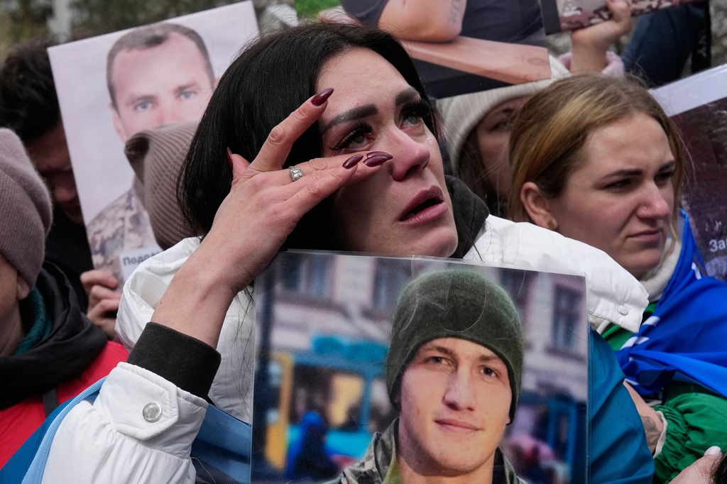 A woman cries as she hold photo of her missed relative as Ukrainian soldiers return from captivity during a POW exchange between Russia and Ukraine in Chernyhiv region, Ukraine, Saturday, April 11, 2026. (AP Photo/Efrem Lukatsky)