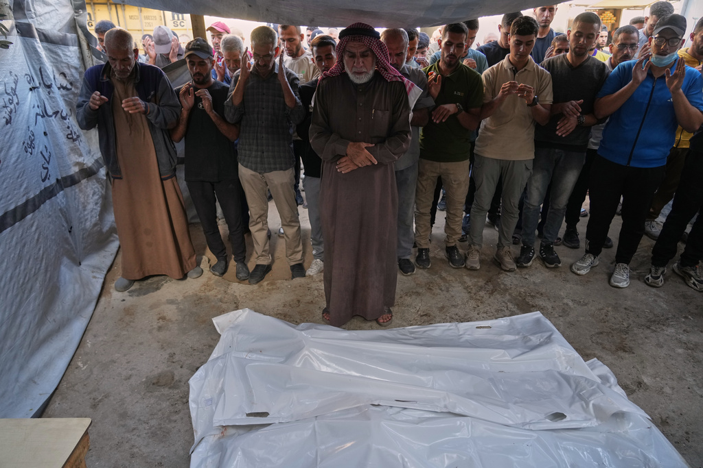 Palestinians pray over the bodies of people who were killed in an Israeli military strike on Sunday, during their funeral at Awda Hospital, in Nuseirat, in the central Gaza Strip, Monday, Oct. 20, 2025. (AP Photo/Abdel Kareem Hana)