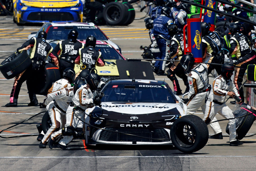 Tyler Reddick, front, and make stop on pit road for a tire change after the first stage during a NASCAR Cup Series auto race at Kansas Speedway in Kansas City, Kan., Sunday, April 19, 2026. (AP Photo/Colin E. Braley)