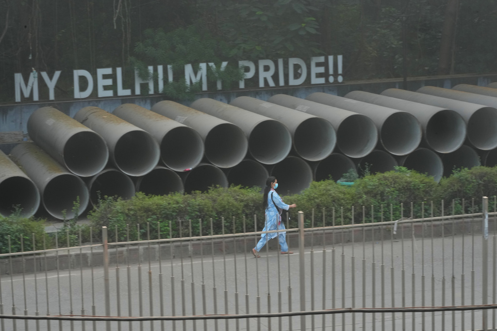 A woman wears a face mask as she walks amidst morning smog a day after Diwali festival in New Delhi, India, Tuesday, Oct. 21, 2025. (AP Photo/Manish Swarup)