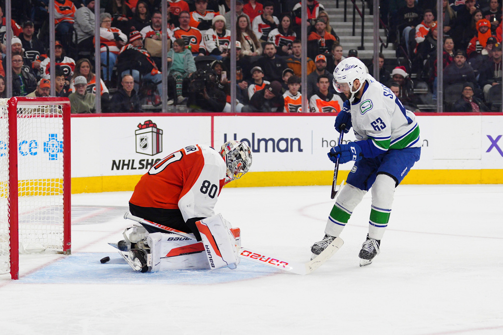 Vancouver Canucks' Max Sasson, right, scores past Philadelphia Flyers goaltender Dan Vladar, left, during the third period of an NHL hockey game, Monday, Dec. 22, 2025, in Philadelphia. (AP Photo/Derik Hamilton)