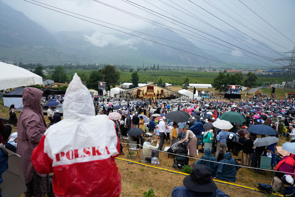 Faithful wait for the start of a consecration ceremony for four new bishops, outside a tent set up outside the Society of St. Pius X seminary, in Econe, Switzerland, Wednesday, July 1, 2026. (AP Photo/Baz Ratner)