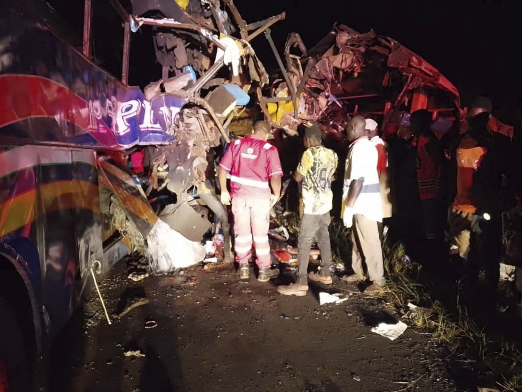 People gather near the wreckage of a bus involved in a collision that left several people dead near Kiryandongo on the highway from the Ugandan capital of Kampala to the city of Gulu in northern Uganda, Wednesday, Oct. 22, 2025. (AP Photo/Uganda Red Cross )