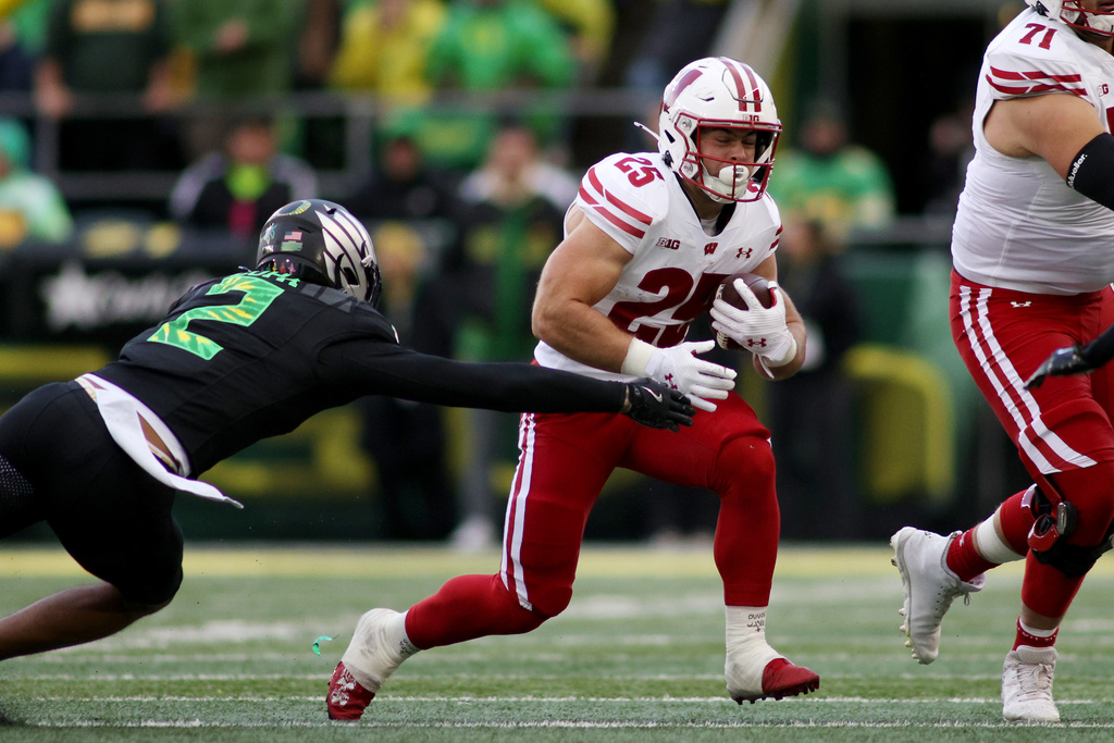 Wisconsin running back Cade Yacamelli (25) attempts to evade a tackle by Oregon defensive back Kingston Lopa (2) during the first half of an NCAA college football game Saturday, Oct. 25, 2025, in Eugene, Ore. (AP Photo/Lydia Ely)
