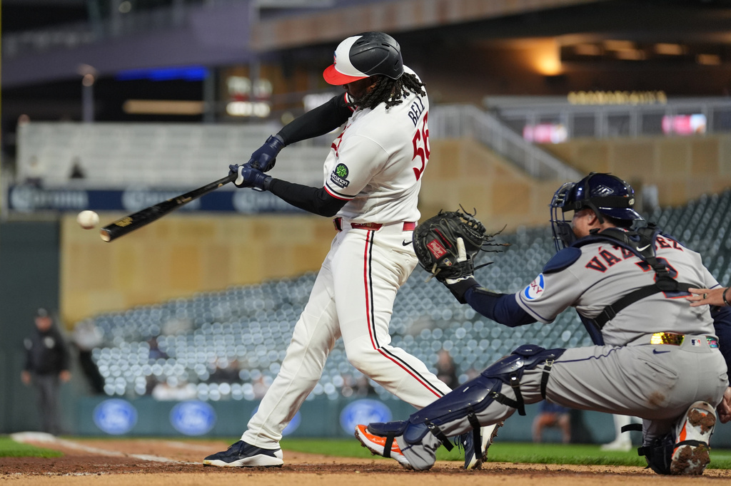 Minnesota Twins'Josh Bell, left, hits an RBI single during the sixth inning of a baseball game against the Houston Astros, Monday, May 18, 2026, in Minneapolis. (AP Photo/Abbie Parr)