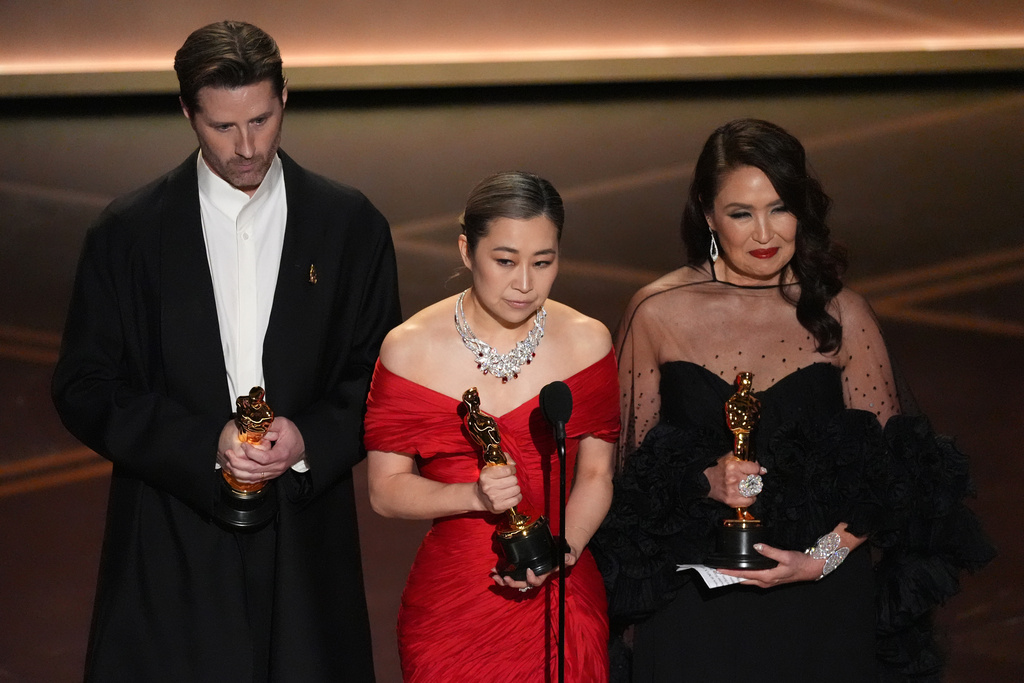 Chris Appelhans, from left, Maggie Kang, and Michelle L.M. Wong accept the award for animated feature film for "K-pop Demon Hunters" during the Oscars on Sunday, March 15, 2026, at the Dolby Theatre in Los Angeles. (AP Photo/Chris Pizzello)
