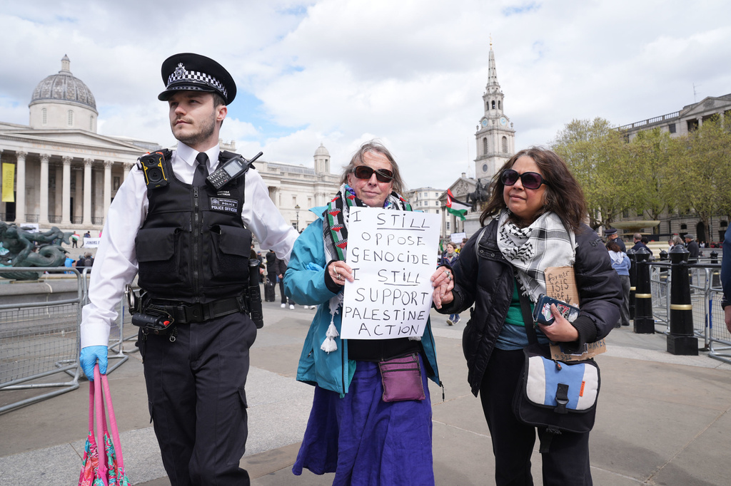 A police officer leads a protester away at a demonstration against the ban on Palestine Action, in Trafalgar Square, central London, Saturday April 11, 2026. (Lucy North/PA via AP)