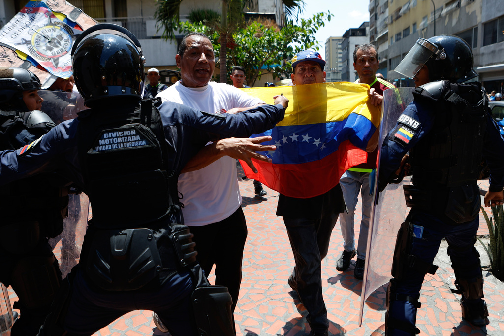 Bolivarian National Police stop protesters who are demanding higher salaries, pensions and benefits, from continuing their march to the Miraflores Presidential Palace in Caracas, Venezuela, Thursday, April 9, 2026. (AP Photo/Pedro Mattey)