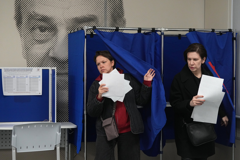 Voters leave voting booths during the parliamentary election in St. Petersburg, Russia, Friday, Sept. 18, 2026, with an image of Soviet novelist Valentin Pikul on the wall. (AP Photo/Dmitri Lovetsky)