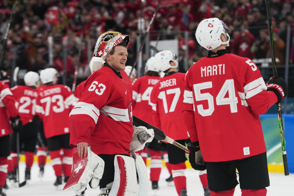 Switzerland's goalkeeper Leonardo Genoni, right, celebrates with teammates after a preliminary round match of men's ice hockey between Switzerland and France at the 2026 Winter Olympics, in Milan, Italy, Thursday, Feb. 12, 2026. (AP Photo/Carolyn Kaster)