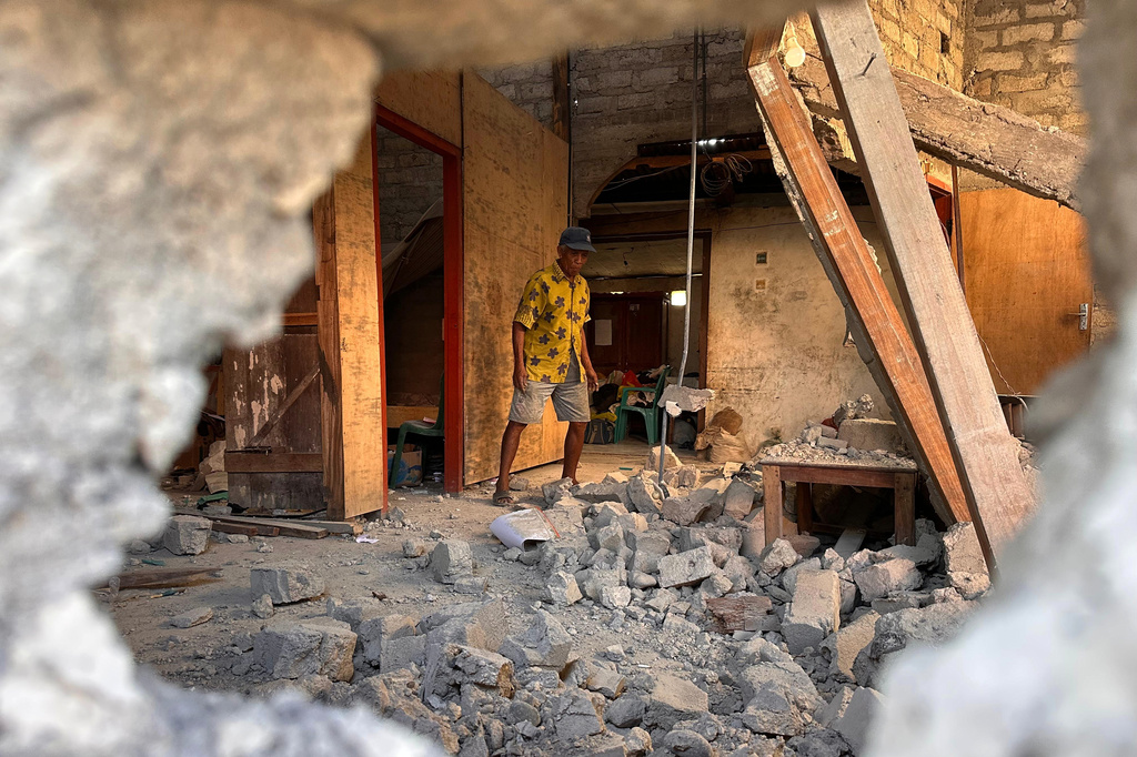 Nicodemus Raja, an earthquake survivor, clears rubble inside his damaged house in North Lamba Leda, East Nusa Tenggara province, Indonesia, Wednesday, Aug. 19, 2026. (AP Photo/Firdia Lisnawati)