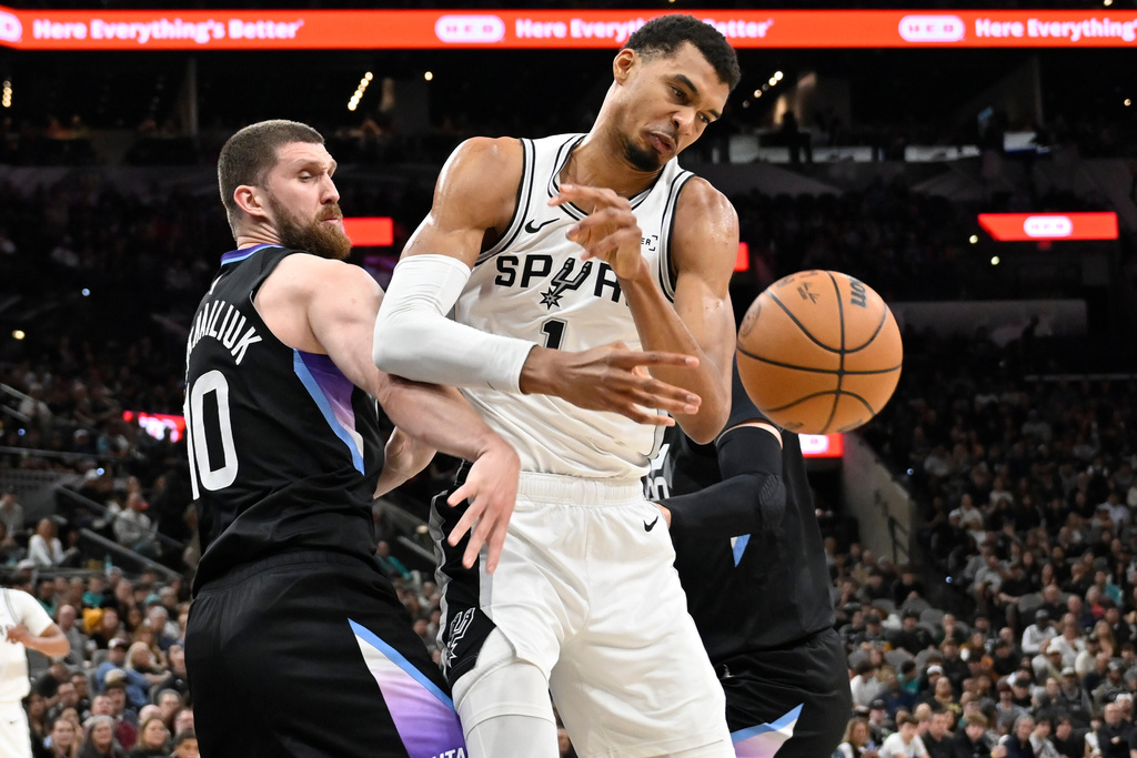 San Antonio Spurs center Victor Wembanyama, right, tangles with Utah Jazz forward Svi Mykhailiuk during the first half of an NBA basketball game, Saturday, Dec. 27, 2025, in San Antonio. (AP Photo/Darren Abate)