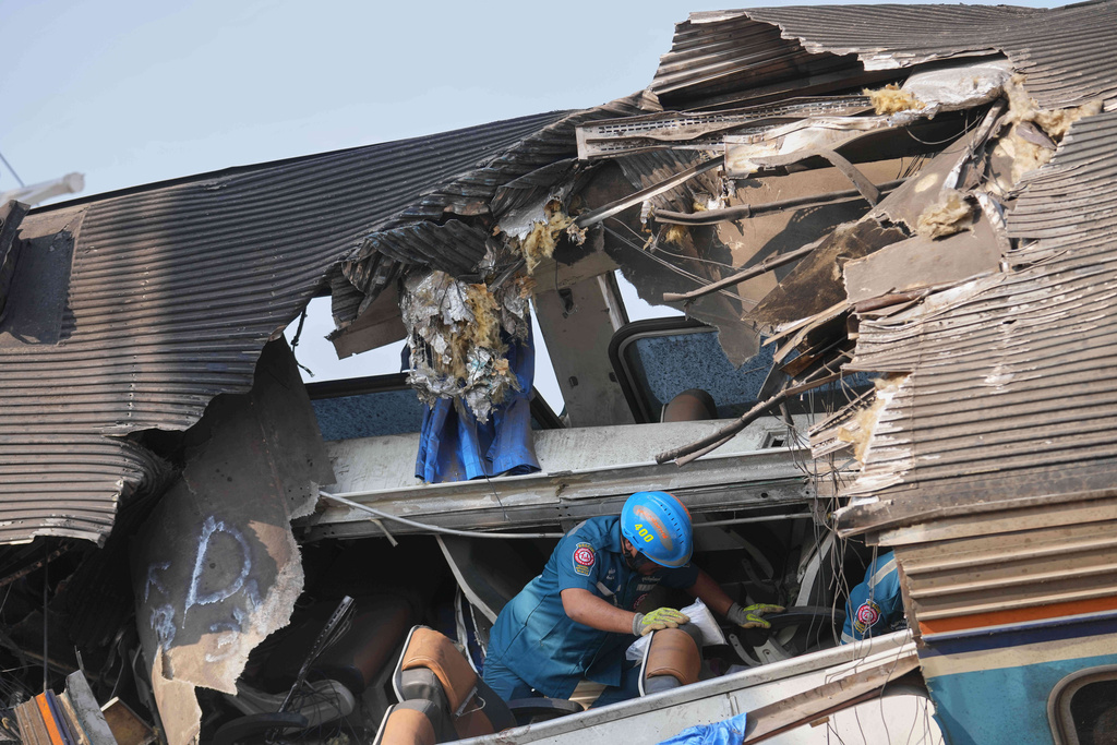 A rescuer searches amidst the wreckage after a construction crane fell into a passenger train in Nakhon Ratchasima province, Thailand, Wednesday, Jan.14, 2026. (AP Photo/Sakchai Lalit))