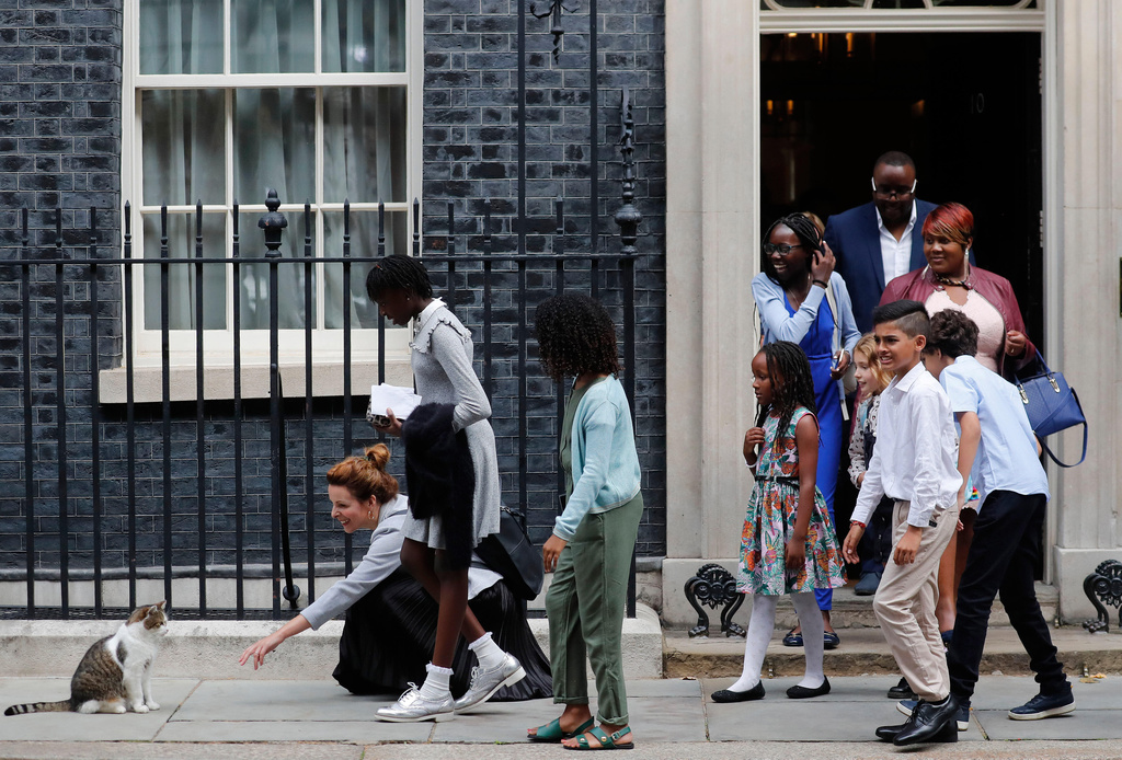 FILE - School children approach Downing Street chief mouser Larry the cat, as they leave after a scheduled meeting with Britain's Prime Minister Boris Johnson at 10 Downing Street in London, Friday, Aug. 30, 2019. (AP Photo/Frank Augstein, File)