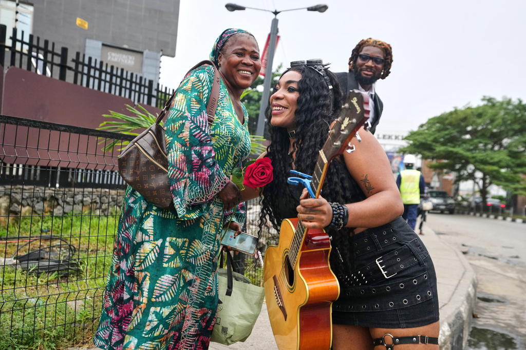 Nigerian rock musician Bianca "Clayrocksu" Okorocha, accompanied by Daniel Onyemachi-Chiweolu, popularly known as Machigold, hugs a woman after giving her a single-stem rose and crooning love songs ahead of Valentine's Day in Lagos, Nigeria, Tuesday, Feb.10, 2026. (AP Photo/Sunday Alamba)