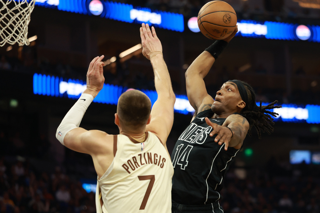 Brooklyn Nets guard Terance Mann (14) shoots against Golden State Warriors center Kristaps Porzingis (7) during the first half of an NBA basketball game in San Francisco, Wednesday, March 25, 2026. (AP Photo/Jed Jacobsohn)