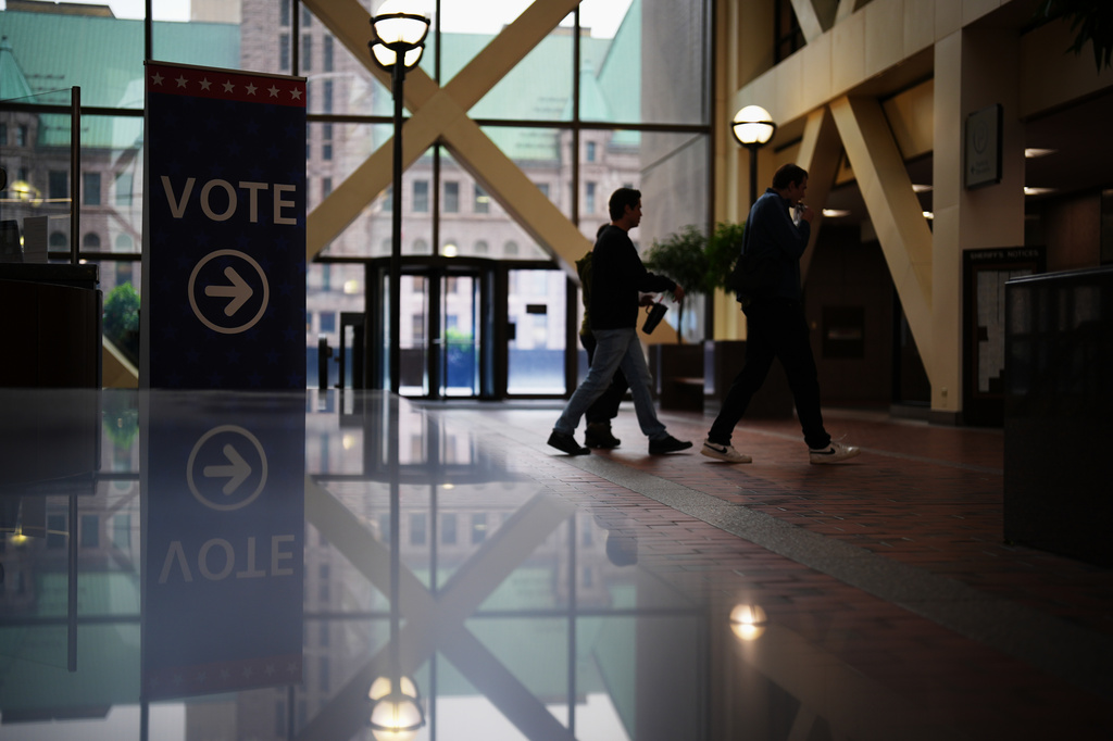 People walk past a sign directing voters on the first day of early voting in Minnesota at the Elections & Voter Services building in Minneapolis, Friday, Sept. 18, 2026. (AP Photo/Ellen Schmidt)