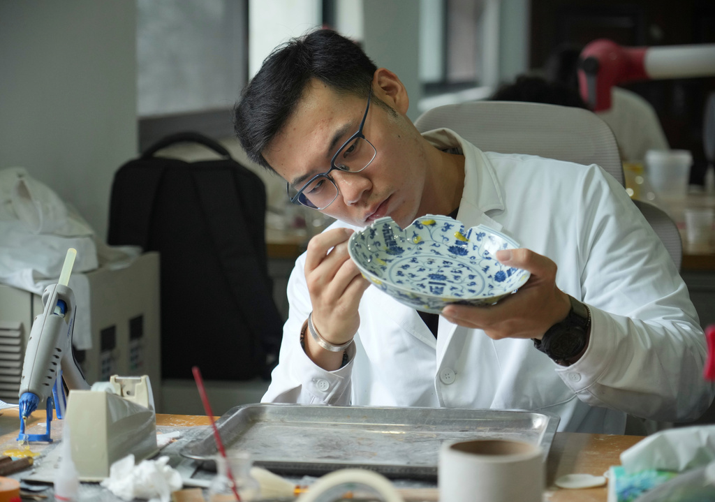 A researcher examines a plate at the Jingdezhen Imperial Kiln Institute which specializes in the research and restoration of ceramics excavated from the city's historic imperial kiln sites in Jingdezhen, in eastern China's Jiangxi province, Monday, Aug. 31, 2026. (AP Photo/Achmad Ibrahim)