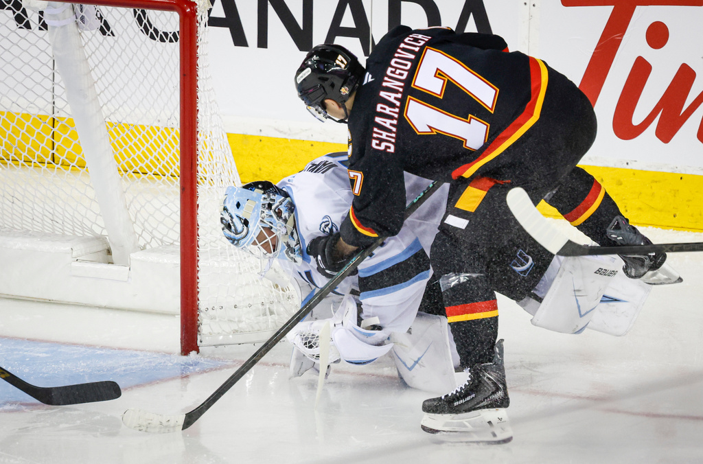 Utah Mammoth goalie Vitek Vanecek, left, collides with Calgary Flames' Yegor Sharangovich during the second period of an NHL hockey game in Calgary, Saturday, Dec. 6, 2025. (Jeff McIntosh/The Canadian Press via AP)