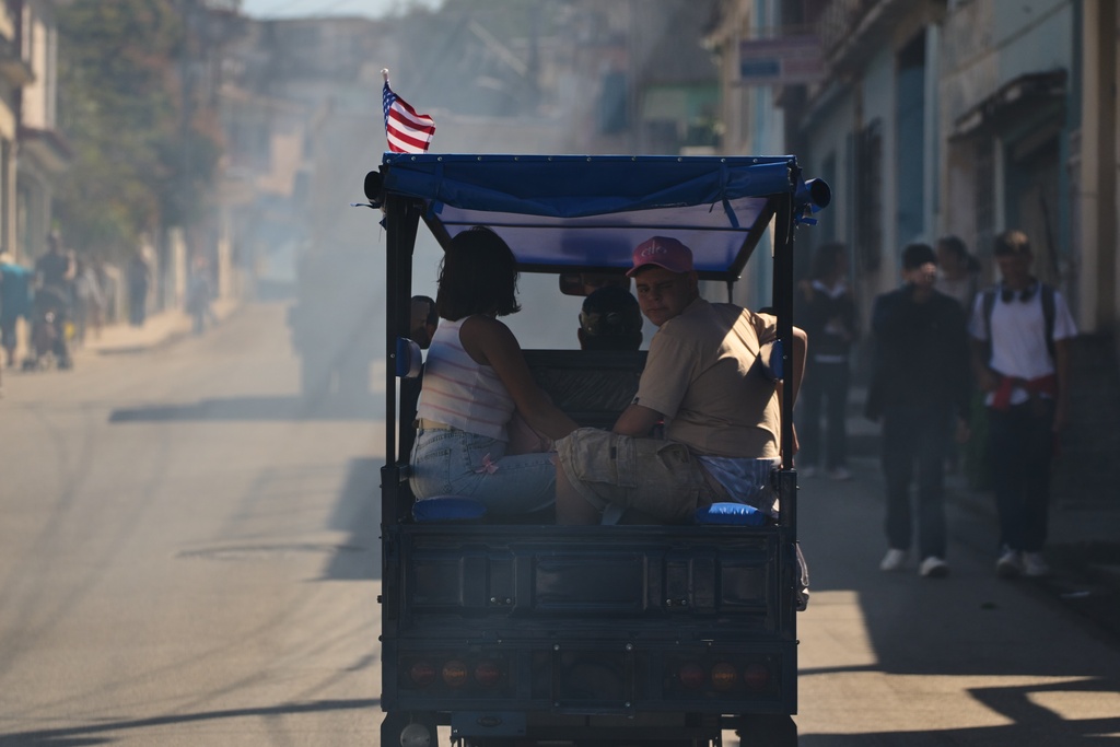 People ride as passengers on an electric tricycle taxi decorated with a U.S. flag in Regla, Cuba, Thursday, Feb. 26, 2026. (AP Photo/Ramon Espinosa)