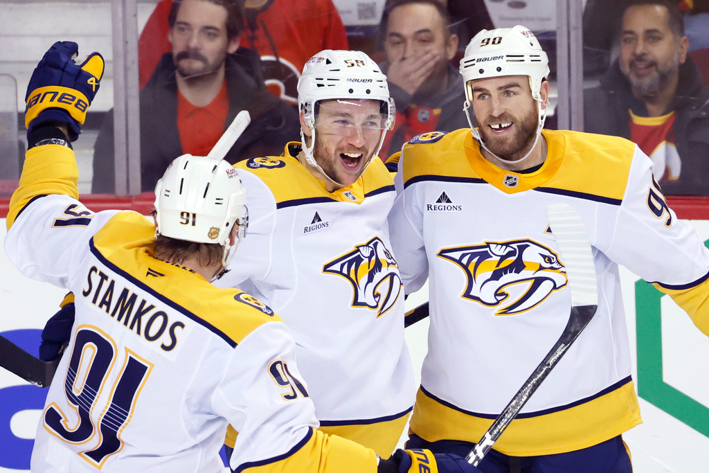 Nashville Predators' Michael Bunting, center, celebrates his goal against the Calgary Flames with Steven Stamkos, left, and Ryan O'Reilly during the second period of an NHL hockey game in Calgary, Alberta, Saturday, Jan. 3, 2026. (Larry MacDougal/The Canadian Press via AP)