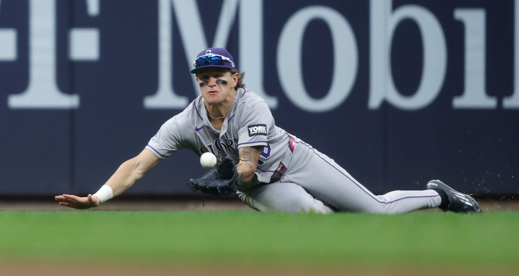Colorado Rockies' Cole Carrigg dives and catches a ball off the bat of the Milwaukee Brewers' Brice Turang during the fifth inning of a baseball game Saturday, July 25, 2026, in Milwaukee. (AP Photo/Jeffrey Phelps)