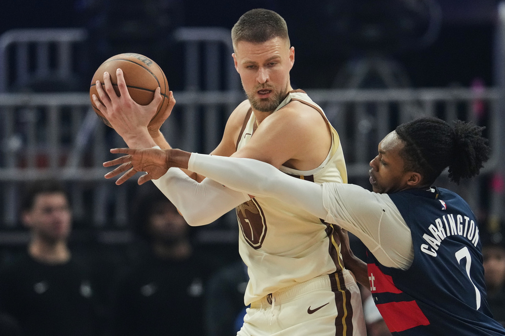 Golden State Warriors center Kristaps Porzingis, left, looks for an open teammate whiel defended by Washington Wizards guard Bub Carrington during the first half of an NBA basketball game, Friday, March 27, 2026, in San Francisco. (AP Photo/Godofredo A. Vásquez)