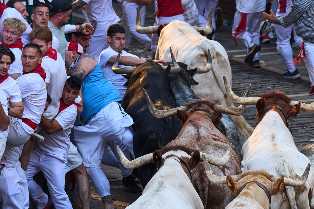 Revelers run alongside Cebada Gago's fighting bulls during the second running of the bulls at the San Fermín festival in Pamplona, Spain, Wednesday, July 8, 2026. (AP Photo/Miguel Oses)
